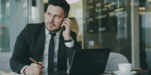 Homme d'affaires en costume passant un appel téléphonique à son bureau devant un portable