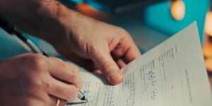 Mains signant un document contractuel au stylo sur un bureau