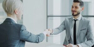 Deux professionnels en costume se serrant la main au-dessus d'une table de bureau